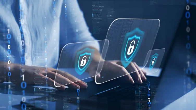 Hands typing on a laptop with digital security icons representing cybersecurity protection.