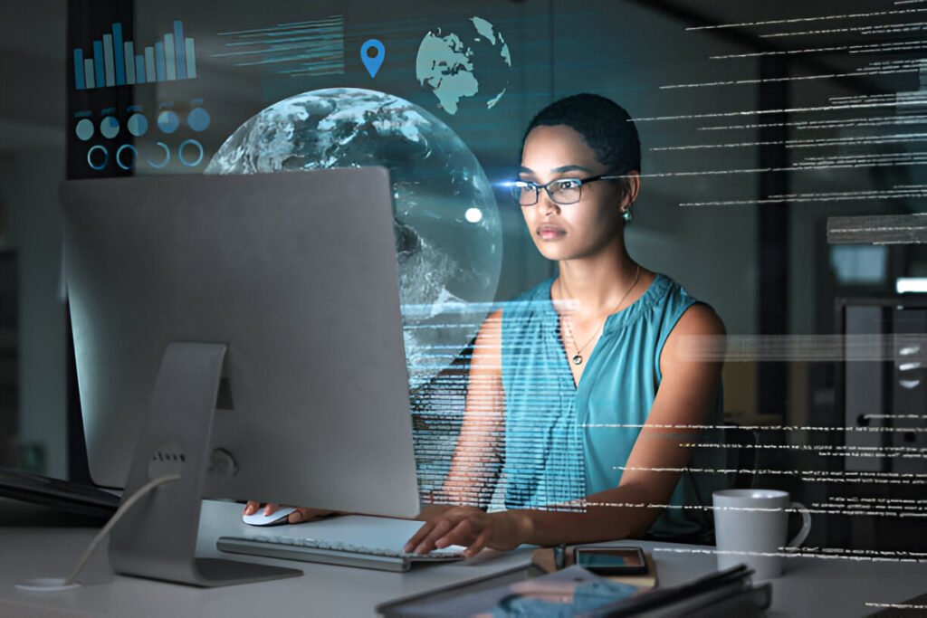 Focused woman working on a desktop computer with global data visualizations and digital analytics overlayed.